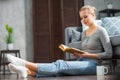 Young blonde girl is reading a book or a textbook. A beautiful woman is resting and relaxing at home. Royalty Free Stock Photo