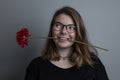 Young blonde girl with a red flower in her mouth Royalty Free Stock Photo