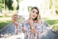 Young beautiful blonde girl relaxing in park, taking a selfie by mobile phone. Royalty Free Stock Photo