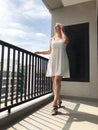 Young girl in short white dress at balcony in summer