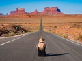 Young blonde girl sits in the center of Forrest Gump Point Road Monument Valley