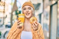 Young blonde girl smiling happy having breakfast at the city