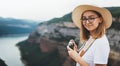 Young blonde girl in summer hat takes photo of  panorama horizin landscape on retro camera leisure during  trip on mountains Royalty Free Stock Photo