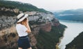 Young blonde girl in summer hat takes photo of  panorama horizin landscape on retro camera during  trip on mountains outdoors Royalty Free Stock Photo