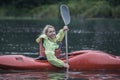 Young blonde girl swims on a sports boat kayak on a beautiful ri Royalty Free Stock Photo