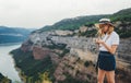 Portrait of brooding young girl with blonde hair in straw summer hat and hipster glasses on backdrop river natura mountain Royalty Free Stock Photo