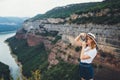 Young blonde girl takes picture on retro photo camera on background panorama horizin mountain and river landscape, hipster tourist Royalty Free Stock Photo