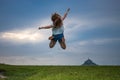 Young, blonde girl taking a big leap, with Mont Saint-Michel in the background Royalty Free Stock Photo