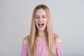 Young blonde girl upset and shouts in the studio on a white background. Royalty Free Stock Photo