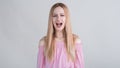 Young blonde girl upset and shouts in the studio on a white background. Royalty Free Stock Photo