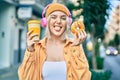 Young blonde girl using headphones having breakfast at the city