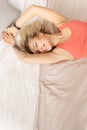 Young blonde girl waking up, looking at the side, smiling. Beautiful woman in a good mood lies on the bed, stretching Royalty Free Stock Photo