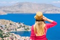 Young blonde girl with wavy hair in straw hat and pink long sleeves shirt is standing on top of the mountain and watching down on Royalty Free Stock Photo