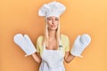 Young blonde girl wearing baker uniform and cook hat looking at the camera blowing a kiss being lovely and sexy