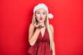 Young blonde girl wearing christmas hat looking at the camera blowing a kiss with hand on air being lovely and sexy Royalty Free Stock Photo