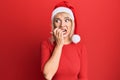 Young blonde girl wearing christmas hat looking stressed and nervous with hands on mouth biting nails Royalty Free Stock Photo