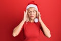 Young blonde girl wearing christmas hat suffering from headache desperate and stressed because pain and migraine Royalty Free Stock Photo