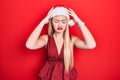 Young blonde girl wearing christmas hat suffering from headache desperate and stressed because pain and migraine Royalty Free Stock Photo