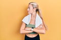 Young blonde girl wearing sportswear and towel looking to the side with arms crossed convinced and confident Royalty Free Stock Photo