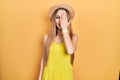 Young blonde girl wearing summer hat covering one eye with hand, confident smile on face and surprise emotion Royalty Free Stock Photo