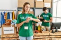 Young blonde girl wearing volunteer t shirt at donation stand checking the time on wrist watch, relaxed and confident