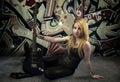 Young blonde holding a black guitar, over grafitti background Royalty Free Stock Photo