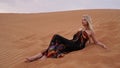 A young blonde lies on a pesce in the desert. Woman in the dunes. Royalty Free Stock Photo
