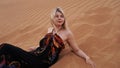 A young blonde lies on a pesce in the desert. Woman in the dunes. Royalty Free Stock Photo