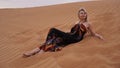A young blonde lies on a pesce in the desert. Woman in the dunes. Royalty Free Stock Photo