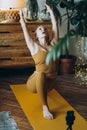 Young woman does yoga poses on mat with phone on tripod