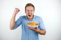 Young blonde man eats chips holding his fist up happily on isolated white background Royalty Free Stock Photo