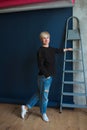 Young blonde modern woman standing near ladder and planning renovation