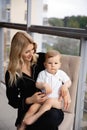 Young blonde mother having quality time with her baby boy son at family home flat - Wearing black budoir dress costume