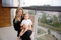 Young blonde mother having quality time with her baby boy son at family home flat - Wearing black budoir dress costume