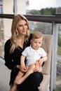 Young blonde mother having quality time with her baby boy son at family home flat - Wearing black budoir dress costume