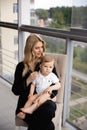 Young blonde mother having quality time with her baby boy son at family home flat - Wearing black budoir dress costume