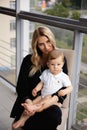 Young blonde mother having quality time with her baby boy son at family home flat - Wearing black budoir dress costume