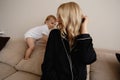 Young blonde mother having quality time with her baby boy son at family home flat - Wearing black budoir dress costume