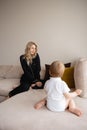 Young blonde mother having quality time with her baby boy son at family home flat - Wearing black budoir dress costume