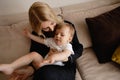 Young blonde mother having quality time with her baby boy son at family home flat - Wearing black budoir dress costume