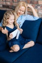 Young blonde mother and her curly little girl look through the photos Royalty Free Stock Photo