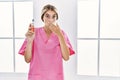 Young blonde nurse woman holding electronic cigarette covering mouth with hand, shocked and afraid for mistake Royalty Free Stock Photo