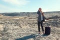 Young blonde in office clothes with a suitcase in the desert among the Sands. The concept of home away from home