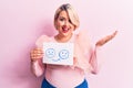 Young blonde plus size woman asking for positive change holding paper with emotion message celebrating achievement with happy