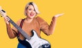 Young blonde plus size woman playing electric guitar celebrating victory with happy smile and winner expression with raised hands Royalty Free Stock Photo