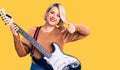 Young blonde plus size woman playing electric guitar pointing finger to one self smiling happy and proud Royalty Free Stock Photo