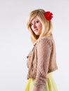 Young blonde with a red gerbera flower in her straight hair, standing in profile and looking at camera Royalty Free Stock Photo