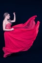 Young Blonde With a Red Silky Dress, That is Flying, in Profile, on Deep Blue Background. Fashion Position Royalty Free Stock Photo