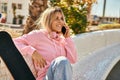 Young blonde skater girl talking on the smartphone and using headphones at the park Royalty Free Stock Photo