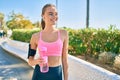 Young blonde sportswoman doing exercise drinking bottle of water at the city